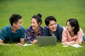 快乐的大学生趴在草地上学习图片