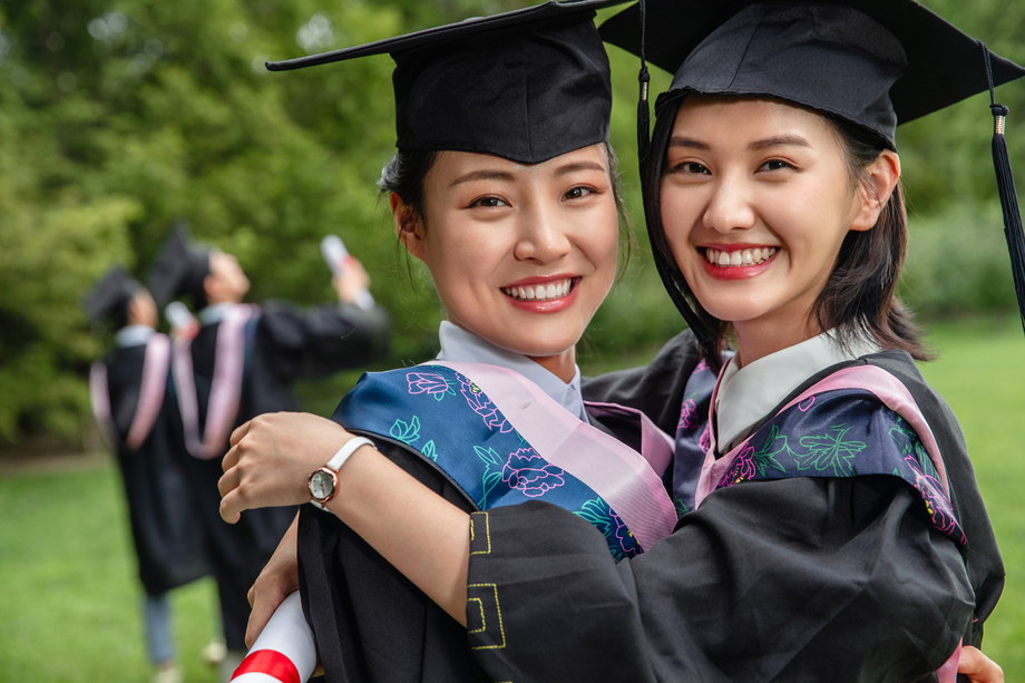 户外穿着学士服的大学生激动的拥抱在一起