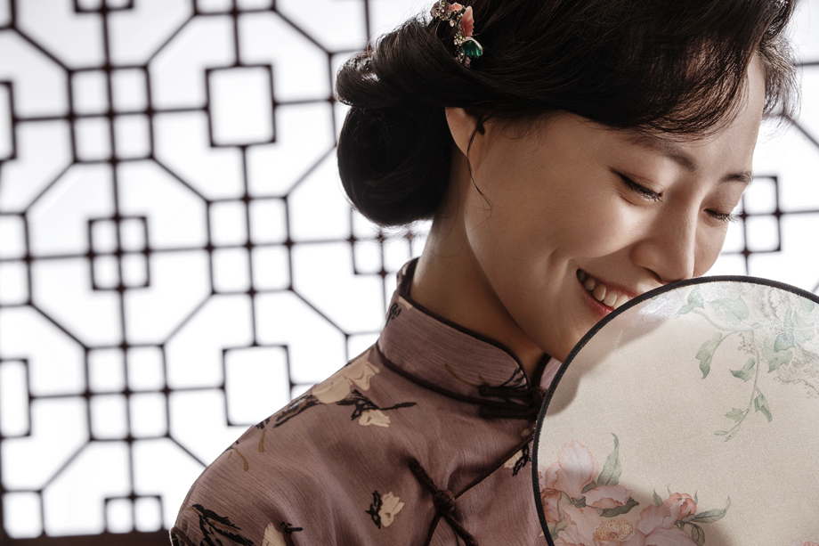 穿旗袍的东方女人躲在扇子后偷笑 穿旗袍的东方女人躲在扇子后偷笑