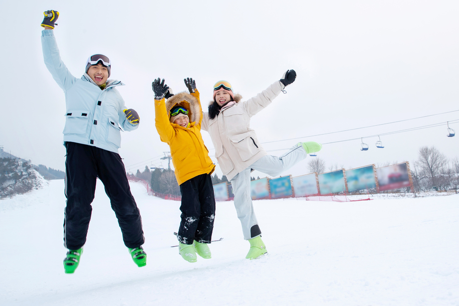 快乐的三口家庭在雪地上嬉戏