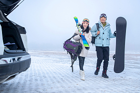 停车场上青年伴侣拿着滑雪板照片