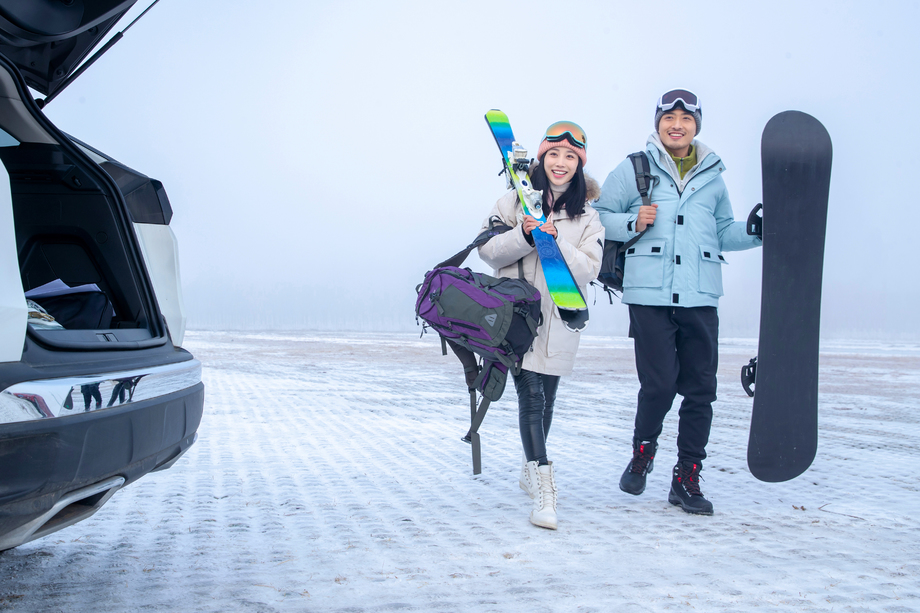 停车场上青年伴侣拿着滑雪板照片