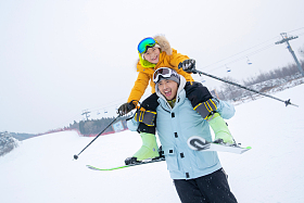 滑雪场上拿滑雪杖的快乐男孩骑在父亲脖子上