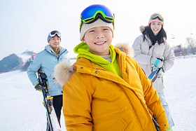 雪场上拿着滑雪板的一家三口照片