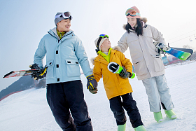 雪场上拿着滑雪板的一家三口照片