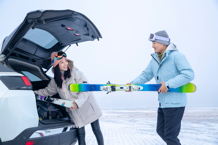 青年夫妻往汽车后备箱里装滑雪板 青年夫妻往汽车后备箱里装滑雪板