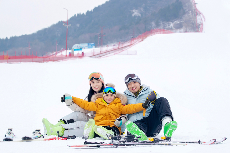 雪场上坐在雪道上的一家三口