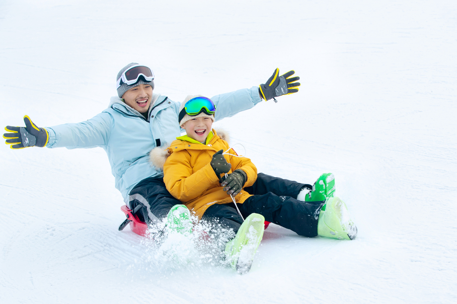 快乐父子坐着雪上滑板滑雪图片 快乐父子坐着雪上滑板滑雪图片