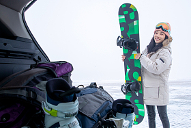 青年女人从后备箱拿单板滑雪板