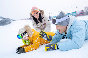 快乐的一家三口趴在雪地上玩雪