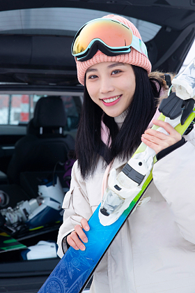 青年女人从汽车后备箱拿滑雪板