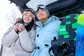 青年伴侣坐在汽车后备箱上看远方