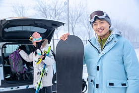 汽车后的青年伴侣拿着滑雪板图片