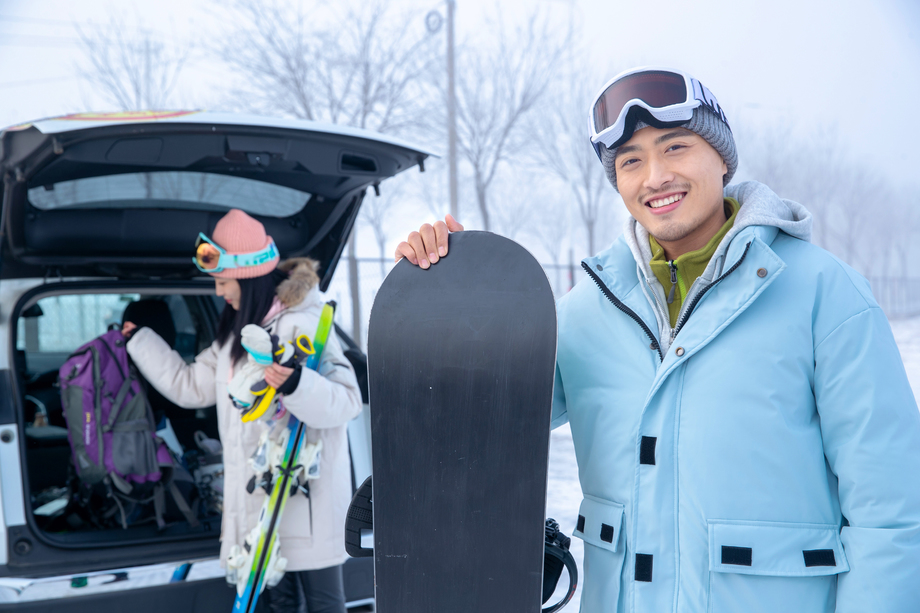 汽车后的青年伴侣拿着滑雪板图片