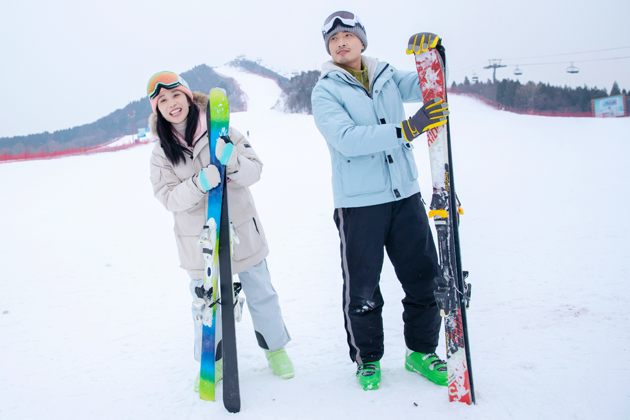 青年伴侣扶着滑雪板站在雪地上 青年伴侣扶着滑雪板站在雪地上