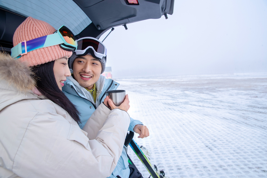 青年伴侣坐在汽车后备箱上喝水闲聊 青年伴侣坐在汽车后备箱上喝水闲聊