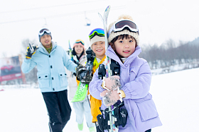 雪场上拿着雪具去滑雪的一家四口