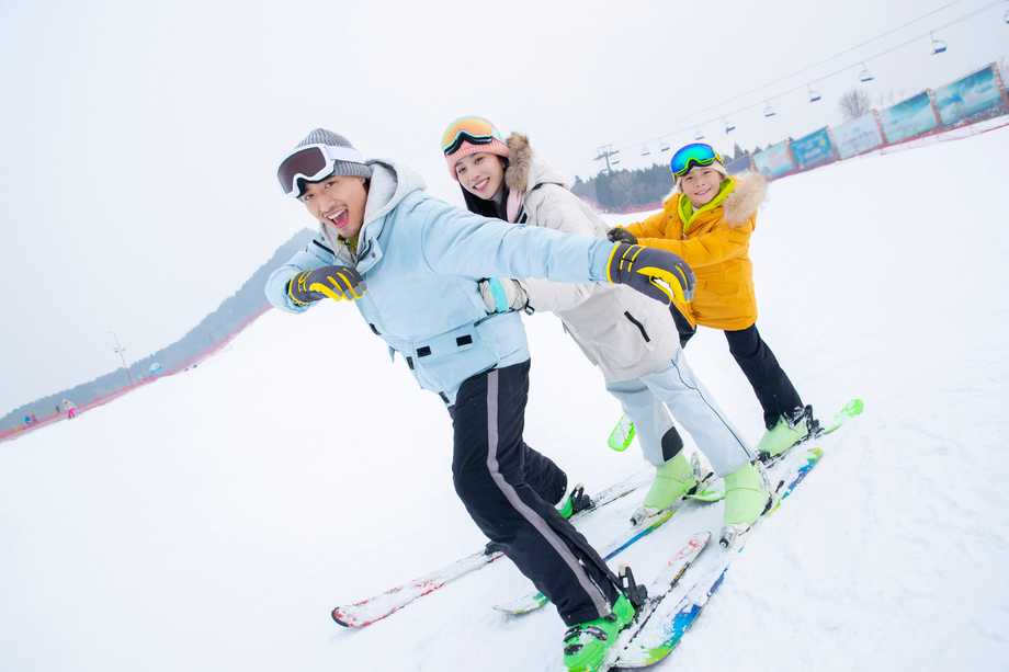 滑雪场上踩着滑雪板排队行走的一家三口