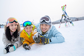 快乐的一家三口趴在雪地上玩雪