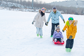快乐的四口之家玩雪上滑板照片