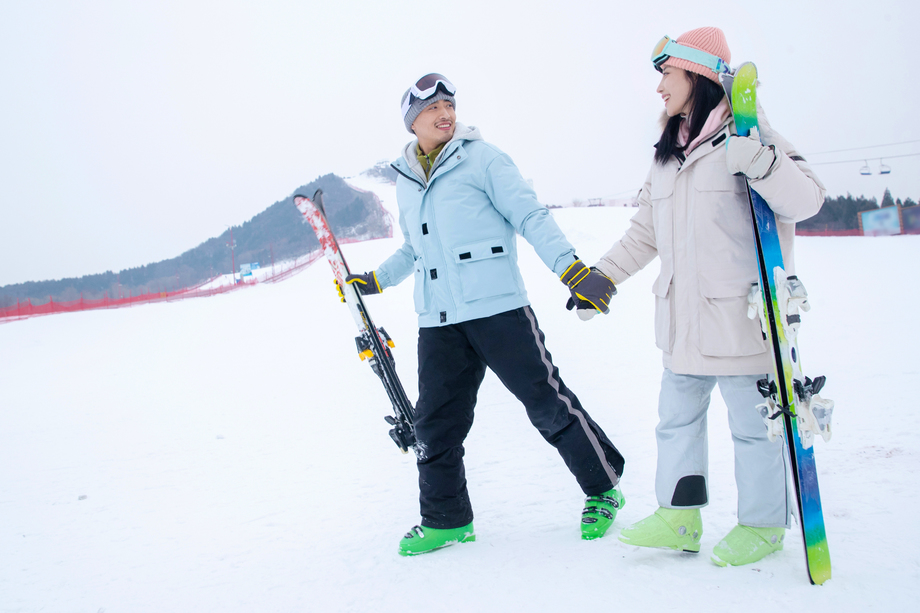 青年伴侣手牵手拿着滑雪板边走边聊 青年伴侣手牵手拿着滑雪板边走边聊