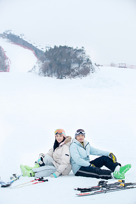 快乐的青年伴侣背靠背坐在雪地上
