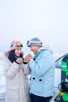 户外青年伴侣靠在汽车上拿着杯子捂手