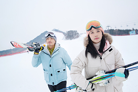 雪场上拿着滑雪板去滑雪的情侣