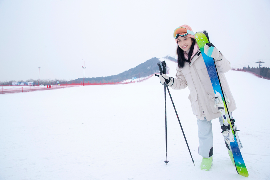 雪场上拿着雪具漂亮的青年女人
