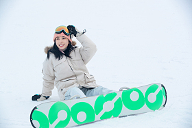 踩着单板坐在雪地上的青年女人