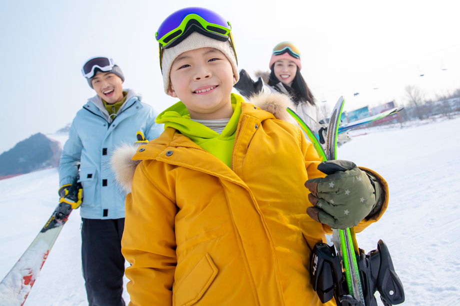 雪场上拿着滑雪板的一家三口图片