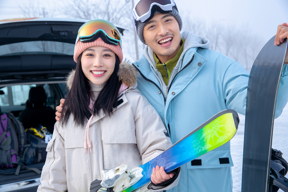 快乐的青年伴侣拿着滑雪板站在一起