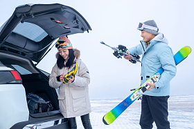 滑完雪的青年伴侣往汽车后备箱里装滑雪板