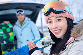 汽车后的年轻情侣扛着滑雪板
