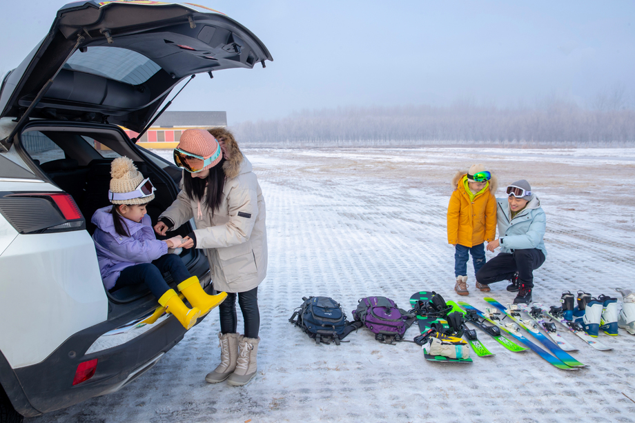 停车场内清点滑雪装备的一家四口 停车场内清点滑雪装备的一家四口