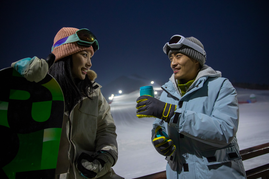 夜晚坐在护栏上喝水聊天的青年伴侣 夜晚坐在护栏上喝水聊天的青年伴侣