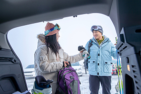 停车场内青年伴侣从汽车后备箱拿雪具