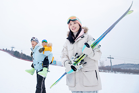滑雪场上背着儿子的父亲和抱着滑雪板的母亲