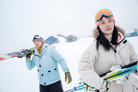 雪场上拿着滑雪板去滑雪的情侣