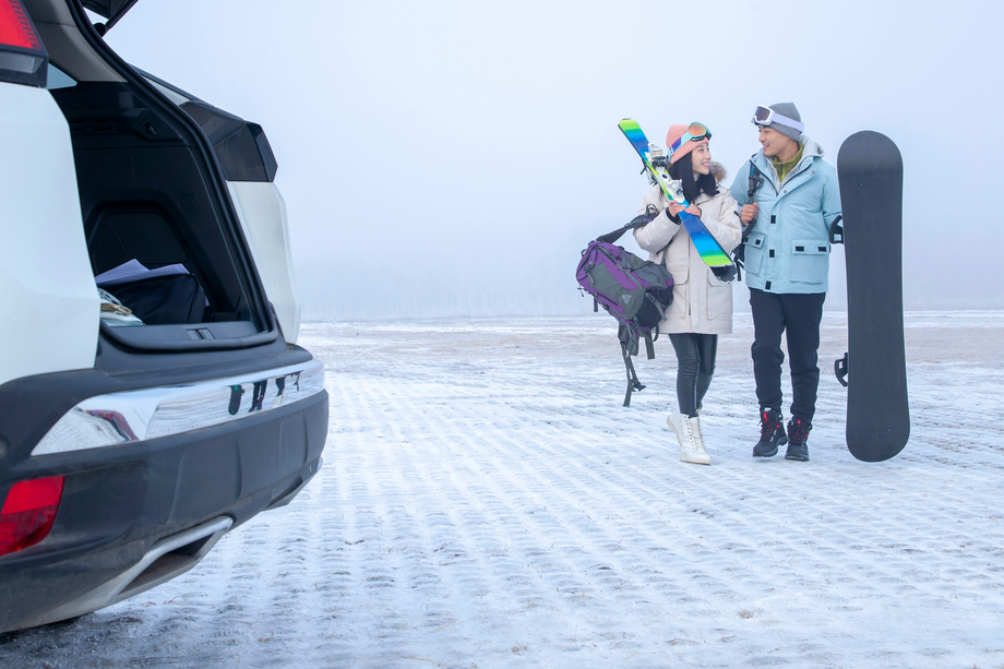 停车场上青年伴侣拿着滑雪板