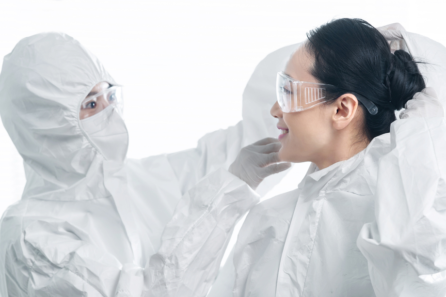 年轻女医生互相协助穿防护服 年轻女医生互相协助穿防护服