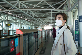 戴口罩的年轻女人站在地铁站台上