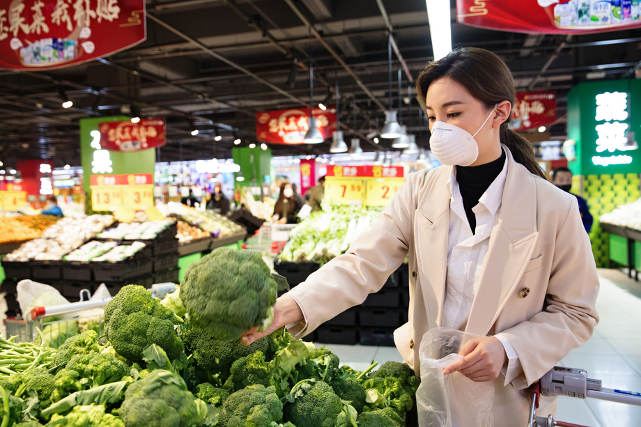 戴口罩的青年女人在超市挑选青菜 戴口罩的青年女人在超市挑选青菜