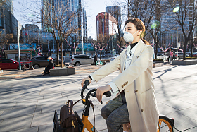 戴口罩的年轻女人骑共享单车图片