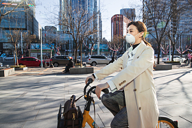 戴口罩的年轻女人骑共享单车照片