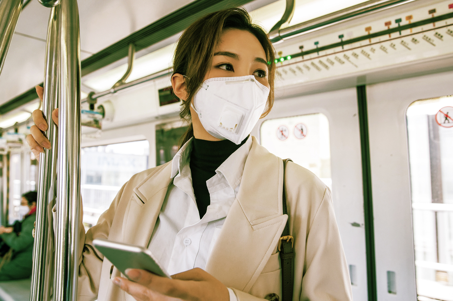 戴口罩的年轻女人乘坐地