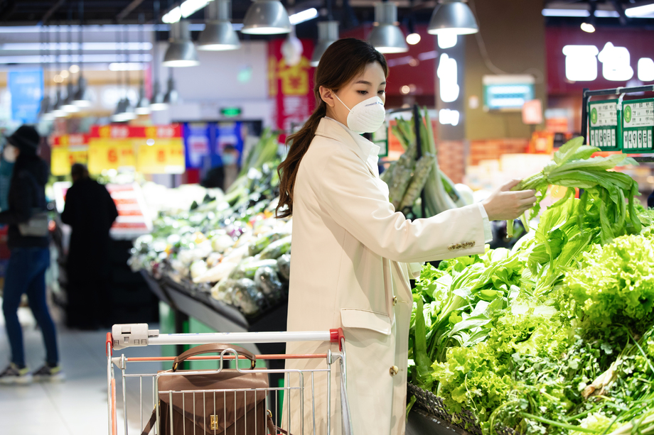 戴口罩的青年女人在超市挑选青菜 戴口罩的青年女人在超市挑选青菜