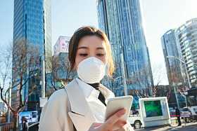 戴口罩的青年女人看手机