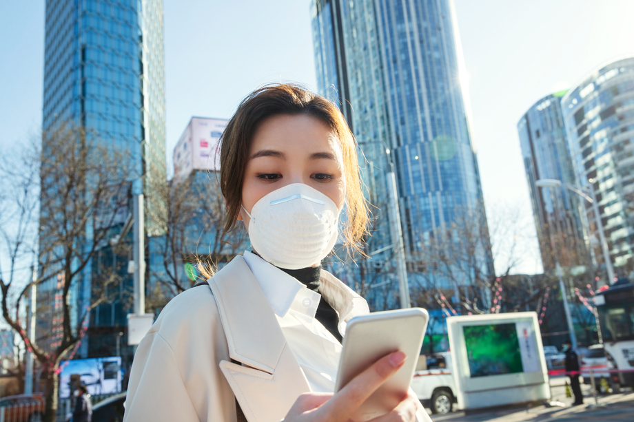 戴口罩的青年女人看手机