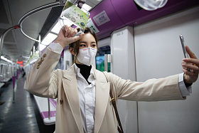 戴口罩的年轻女人在地铁里看手机